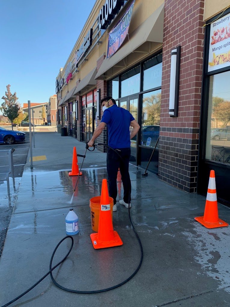Sosa Cleans team member pressure-washing a storefront sidewalk